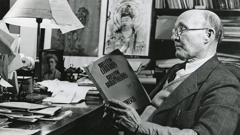 Edward Church sits in an office reading a book. Campus Images Collection, UNRA-P1747-1. University Archives.