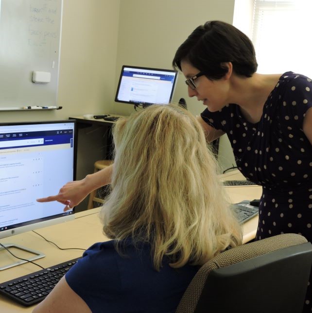 A library instructor pointing to something on a student's computer screen