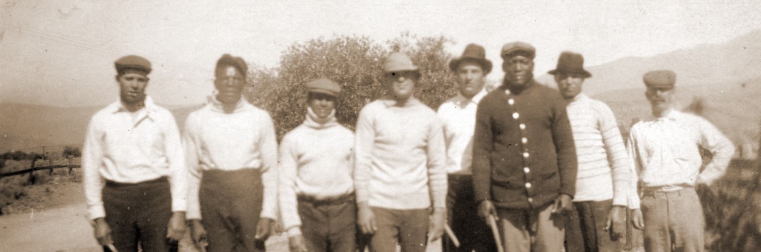 Jack Johnson and his entourage standing in a field with sticks