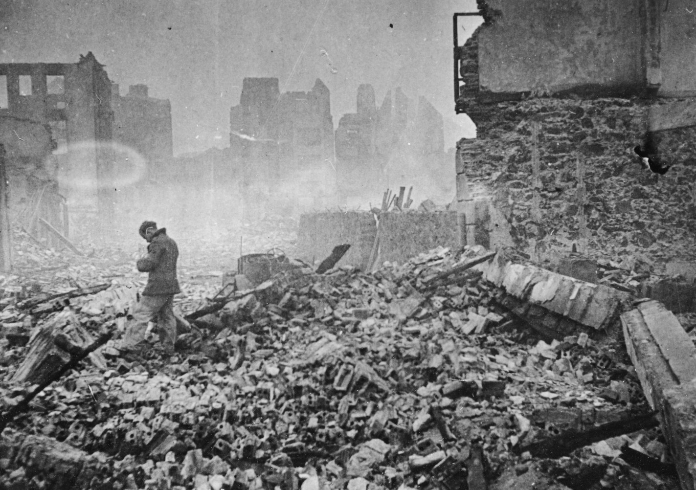 Black and white photo of Joseba Elosegi standing in a pile of smoking rubble