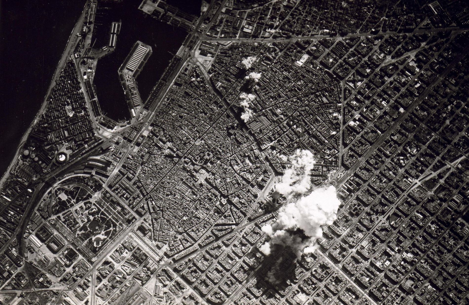 Aerial black and white view of Barcelona with bombs exploding