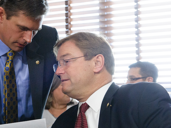 Image of Dean Heller being whispered to by another person.