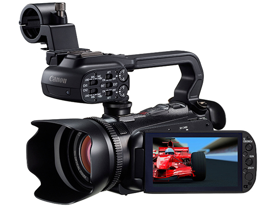 Black Canon XA 10 with large lens, mounts for microphones, and a viewfinder showing a blue and red screen