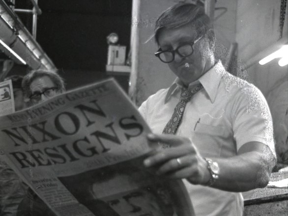 A man stands reading a newspaper.