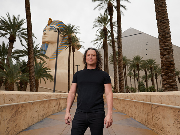 Jarret Keene stands posed in front of a pyramid.
