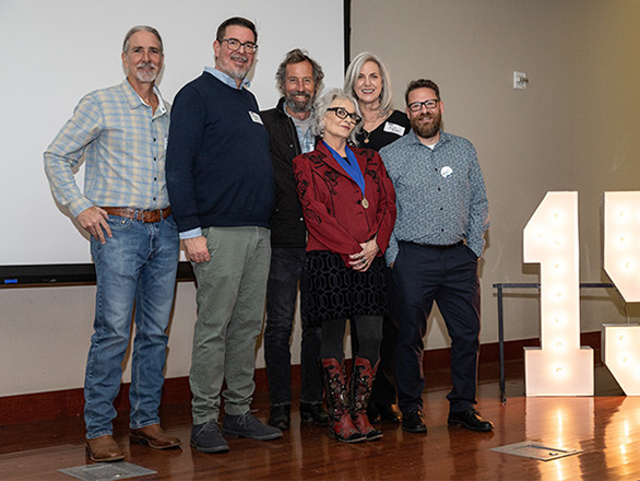 Six people stand by a lit up 150 sign at the 37th Nevada Writer's Hall of Fame.