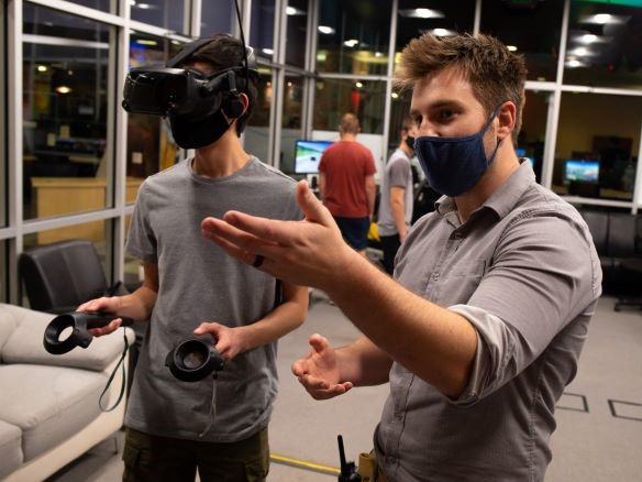 An instructor teaching a student wearing a VR visor in the At Reality lab