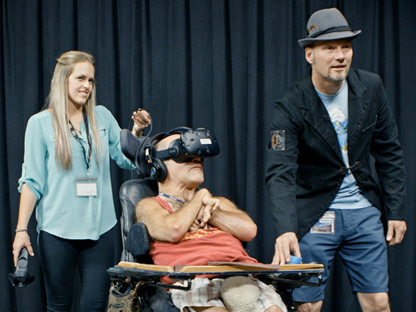 Two Library employees assist a man in a wheelchair as he explores virtual reality with a VR headset.
