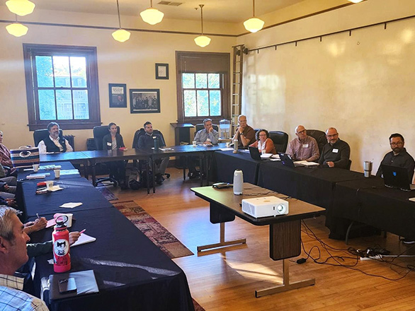People sit around a table in a large, well-lit room.