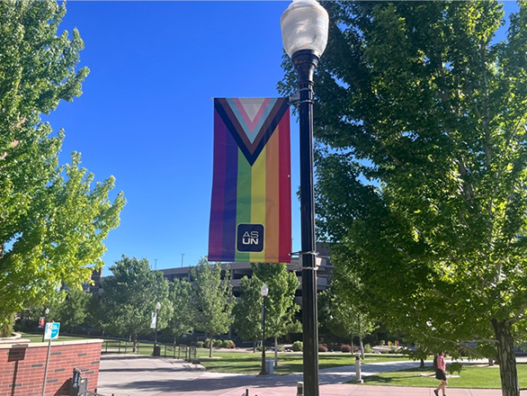 Campus light post with a pride flag on it, labeled with "ASUN".