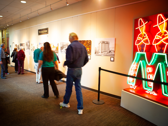 Members of the public walking past an exhibit of local neon on the Third Floor of the Knowledge Center.
