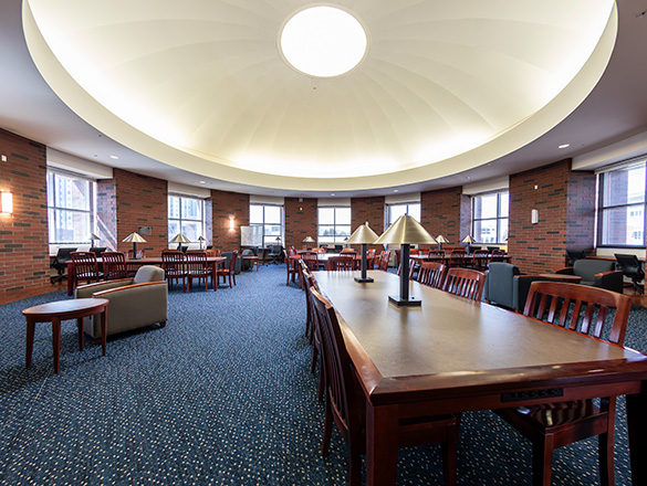 Wide angle shot of the Hilton Rotunda Reading Room showing many tables and several comforatble chairs.