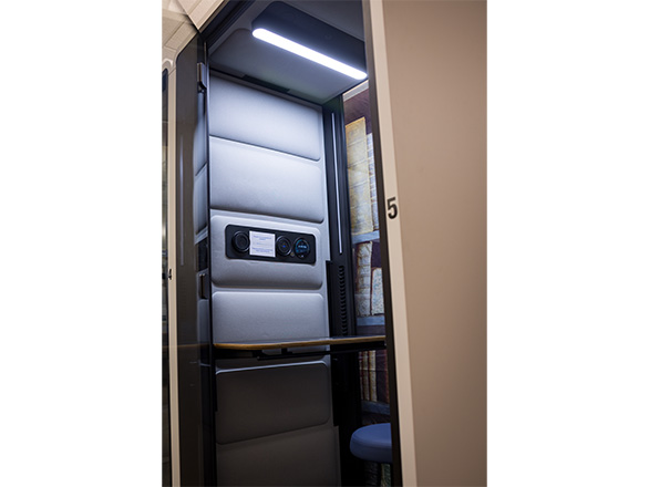 Close up shot of a narrow study pod with overhead lighting and soundproofed walls.