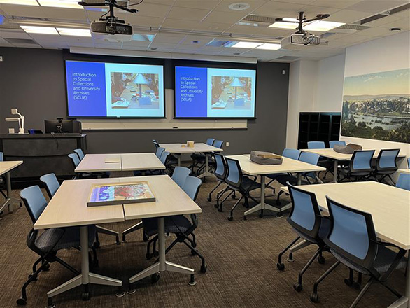 View of the Vault classroom with tables and two large screens at the front of the room.