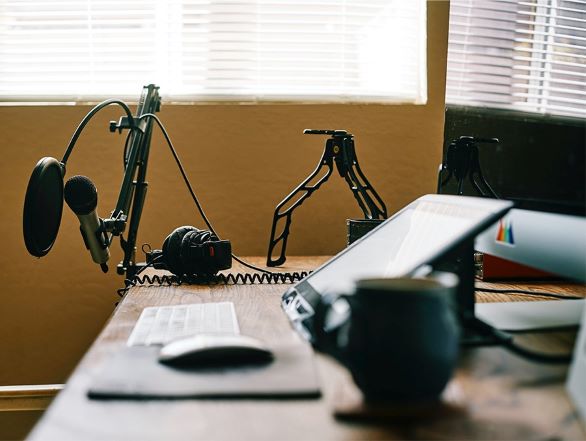 Desk with microphone equipment and laptop set up for podcasting