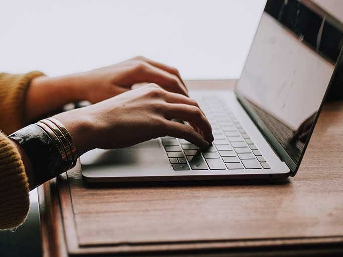 Hands typing on a laptop computer