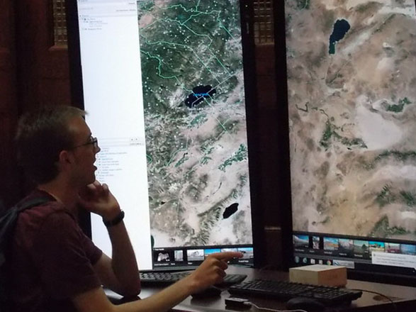 Student looking at colorful maps on large computer monitors