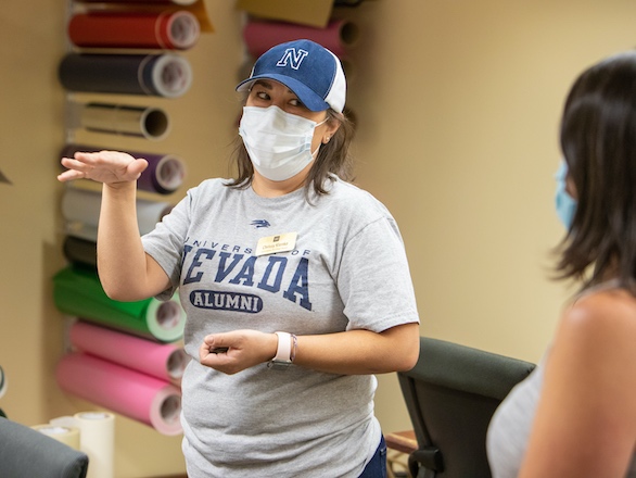 Team member at DeLaMare talking to a student while wearing a mask.