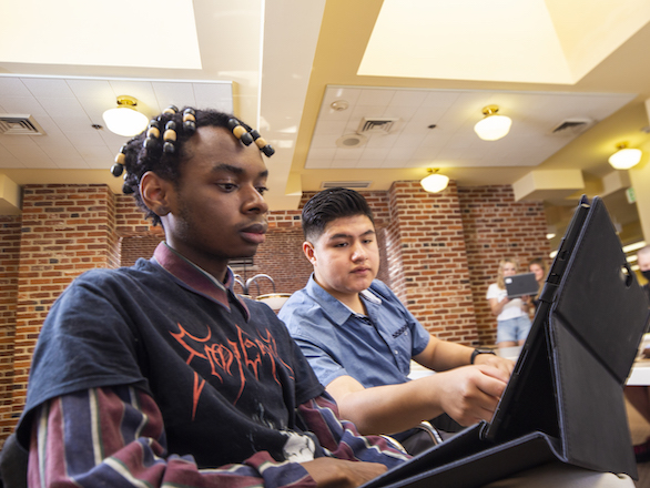Students working with a tablet in the DeLaMare library.