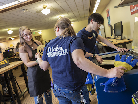 Team members working with students using a fabrication mill in the Makerspace.