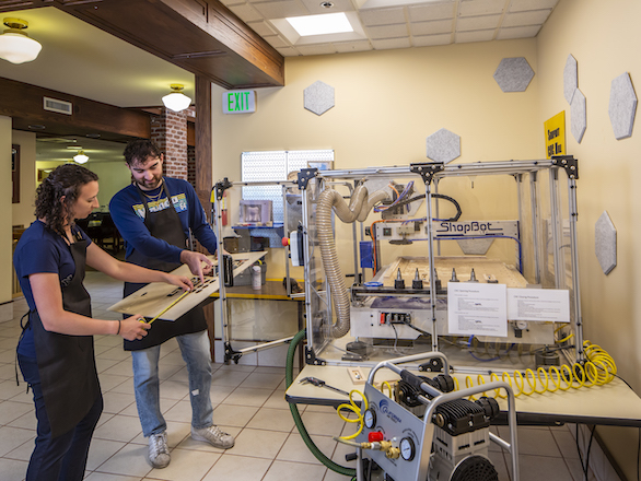 Makerspace team members reviewing a project in front of fabrication equipment.