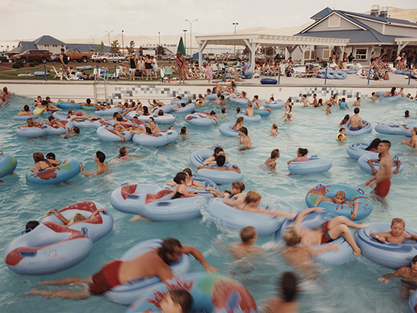 A group of people float on inner tubes in a lazy river. UNRS-P2015-14-00663.