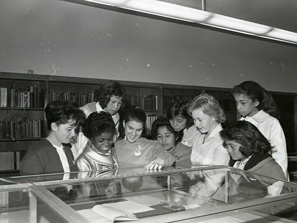 Native American girls look into an exhibit case in Getchell Library during a tour sponsored by the YWCA. UNRA-P429-06.tif, collection_4079.