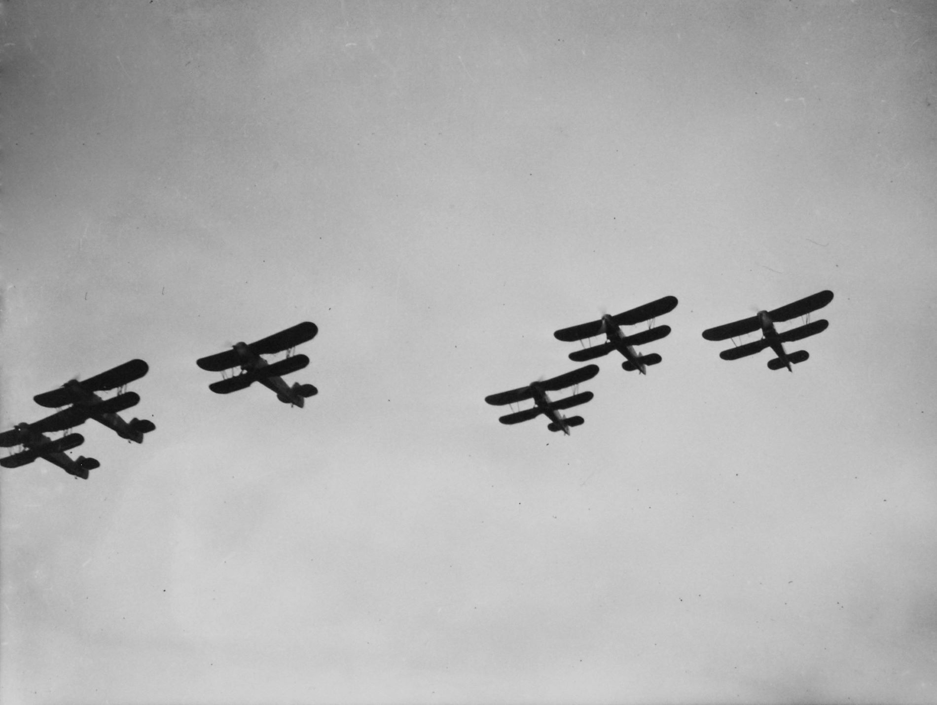 Black and white image of planes flying in chains as seen from the ground