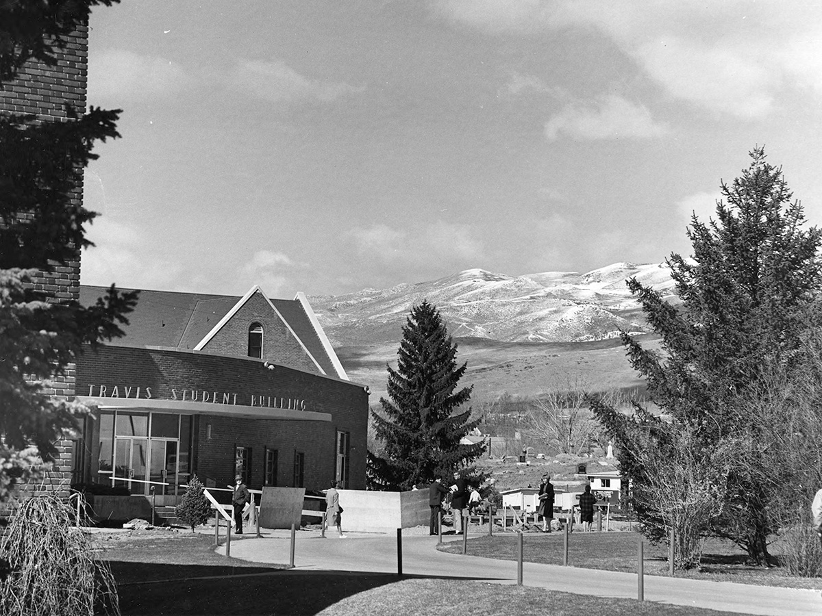 Students walk along the walkway near the Jot Travis Student Union. Peavine Peak and the old cemetery are visible in the background.