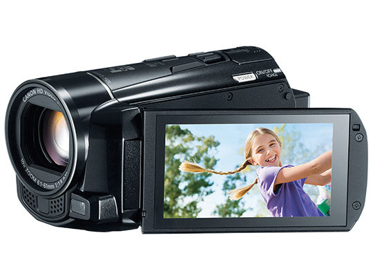 Black handheld Canon M5000 with viewfinder displaying a girl with long braids playing near a tree