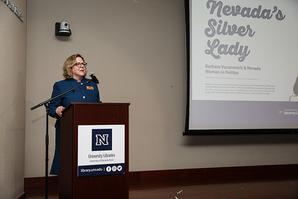 Dean Cardwell stands at a podium. A screen behind her reads "Nevada's Silver Lady".