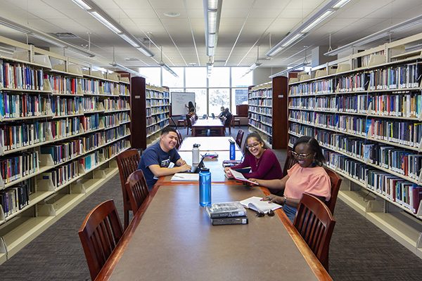 Students sit at a table in the Knowledge Center stacks.