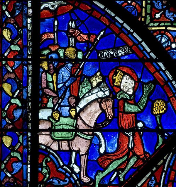 A vibrant stained glass window depicting men on horseback led by a praying Charlemagne.