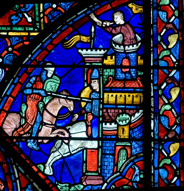 A vibrant stained glass window showing a soldier on a horse approaching a castle.