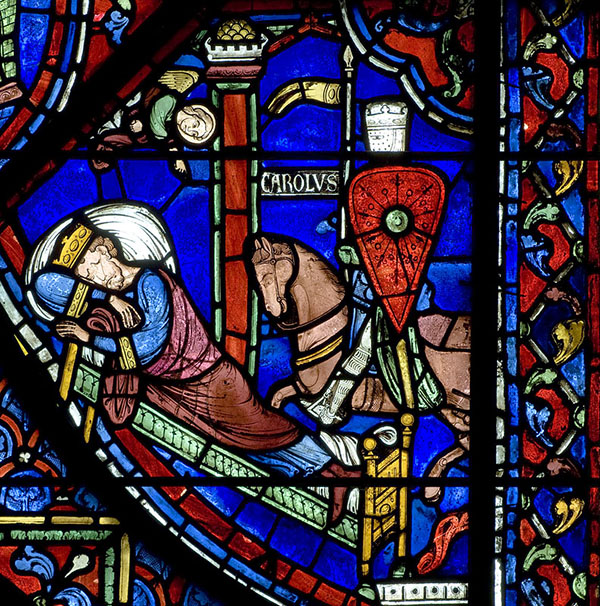 A vibrant stained glass window depicting a man sleeping and receiving word from God.