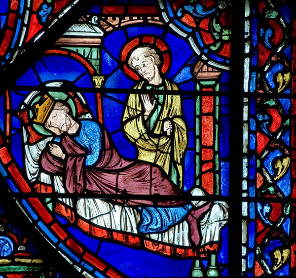 A vibrant stained glass window depicting Charlemagne sleeping and a man standing behind him.