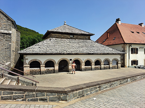 A pit in front of a building with arched entryways.