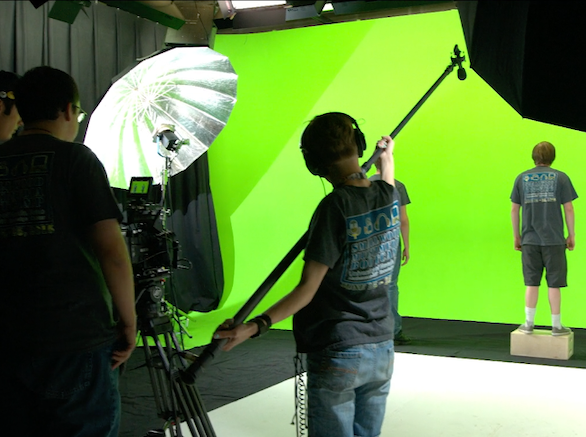 Camp participants working with a boom microphone and green screen.